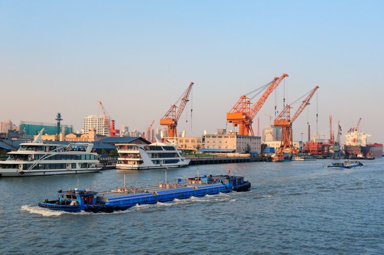 Boat in Huangpu River with Shanghai urban architecture and cargo crane